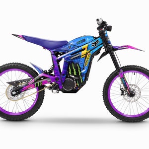 Könnte beinhalten: Ein schwarzes und blaues Elektro-Dirt-Bike mit einer violetten Felge und einem Monster-Energy-Logo. Das Fahrrad hat ein blaues, violettes und pinkfarbenes Grafikdesign mit dem Text "Valkyrie" und "Fox" an der Seite.