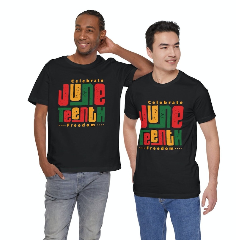 Puede incluir: Dos personas con camisetas negras con un dise&ntilde;o gr&aacute;fico que dice "Celebrate Juneteenth...Freedom..." en rojo, amarillo y verde.