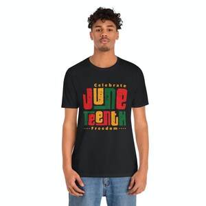Puede incluir: Una camiseta negra con un dise&ntilde;o gr&aacute;fico que dice "Celebrate Juneteenth...Freedom..." en letras rojas, amarillas, verdes y negras.