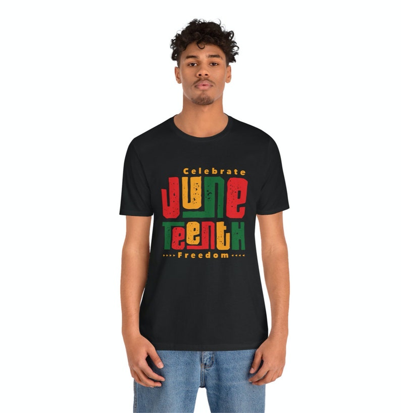 Puede incluir: Una camiseta negra con un dise&ntilde;o gr&aacute;fico que dice "Celebrate Juneteenth...Freedom..." en letras rojas, amarillas, verdes y negras.