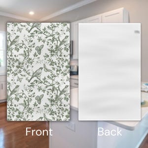 May include: A white kitchen tea towel with a green and white floral pattern featuring birds and butterflies on the front. The back of the towel is plain white.