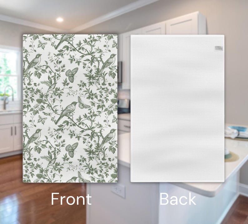 May include: A white kitchen tea towel with a green and white floral pattern featuring birds and butterflies on the front. The back of the towel is plain white.