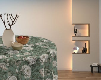 May include: A round green tablecloth with a white floral pattern. The tablecloth is on a round table with a white vase and a bowl of fruit on it.