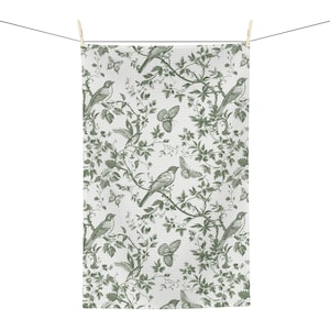 May include: A white kitchen towel with a green floral pattern featuring birds and butterflies. The pattern is repeated throughout the towel.