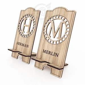Op de afbeelding: Twee houten telefoonstandaards met gepersonaliseerde initialen en namen. De standaard links heeft de letter "H" en de naam "HERMAN". De standaard rechts heeft de letter "M" en de naam "MERLIN".