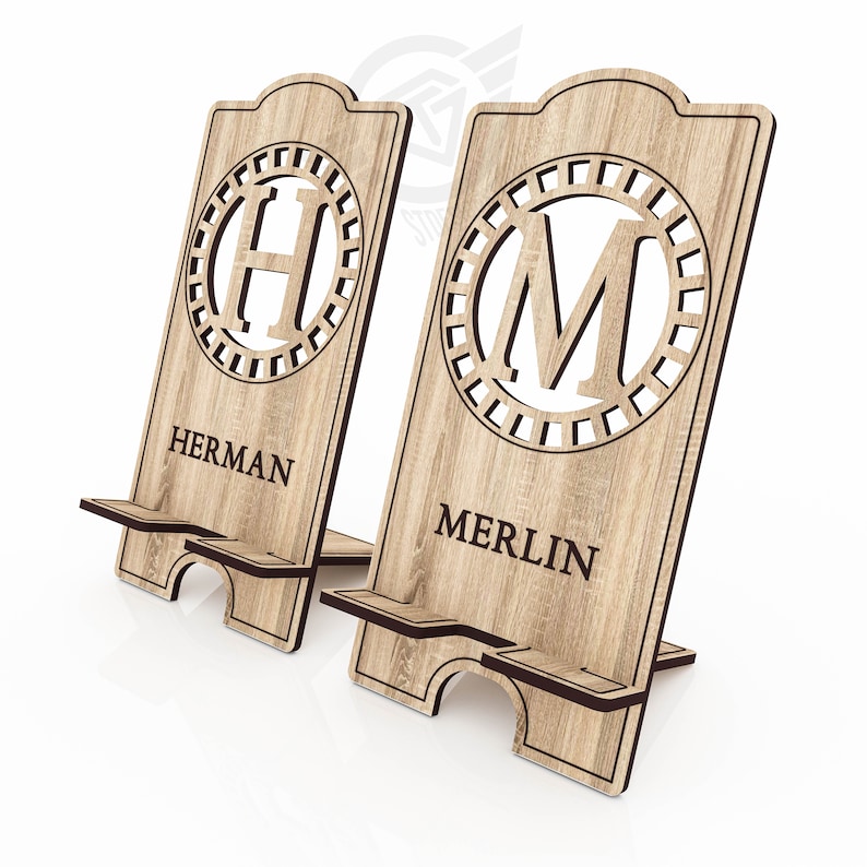 Op de afbeelding: Twee houten telefoonstandaards met gepersonaliseerde initialen en namen. De standaard links heeft de letter "H" en de naam "HERMAN". De standaard rechts heeft de letter "M" en de naam "MERLIN".