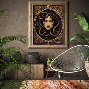 May include: A framed illustration of Medusa, a mythical Greek figure with snakes for hair, depicted in a dark, ornate frame with gold accents. The illustration is set against a brown wall with a potted plant and a chair in the background.