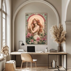 May include: A digital art print featuring a woman with long red hair standing in a field of pink flowers. The woman is wearing a white dress and has a halo of light around her head. The print is framed in a decorative border.