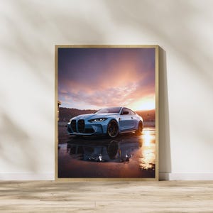 May include: Framed print of a light blue sports car with black wheels, parked on a wet surface. The car is reflected in the water. The background features a sunset with orange and purple hues.