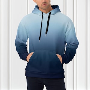 May include: A hooded sweatshirt with a gradient design, transitioning from light blue at the top to a deep navy blue at the bottom. The hoodie features a front pocket and black drawstrings.