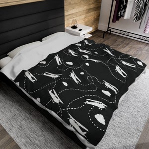 Puede incluir: Bedding negro y blanco con un patrón repetido de aviones volando en un camino de puntos. Los aviones son blancos y el fondo es negro.