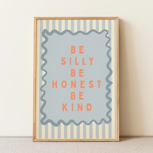 May include: A rectangular wall art print in a light wood frame featuring a light blue and cream vertical striped background. A central grey scalloped-edge rectangle contains the orange text: BE SILLY, BE HONEST, BE KIND, arranged in five lines.
