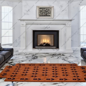 May include: Two terracotta-colored rugs with a repeating navy blue arrow and geometric pattern are displayed in front of a fireplace. The rugs are rectangular and placed on a marble floor. The room has a modern design.