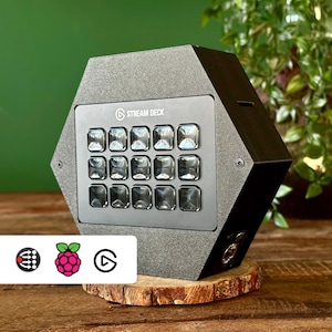 May include: A black hexagonal Stream Deck with 15 customisable buttons and a textured surface. The Stream Deck is sitting on a wooden surface.