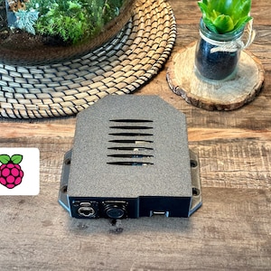 Könnte beinhalten: Ein schwarzes Raspberry Pi-Gehäuse mit einer Lüftung oben und Anschlüssen vorne.