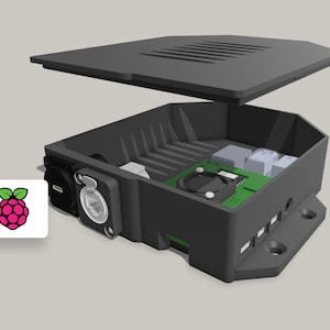Könnte beinhalten: Ein schwarzes Raspberry Pi-Gehäuse mit einem abnehmbaren Deckel, der die inneren Komponenten zeigt, darunter einen kleinen Lüfter und eine grüne Platine.