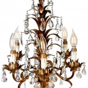 May include: Ornate gold chandelier with crystal accents. The fixture features multiple arms with candle-style light bulbs and dangling crystal droplets. The design has a vintage, elegant aesthetic, suitable for interior lighting.