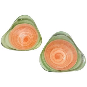 May include: Two decorative, free-form shaped bowls. Each bowl features a spiral design with a center of orange, surrounded by concentric rings of peach and green. The bowls are made of a glossy material.