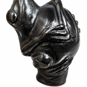 May include: A dark bronze frog sculpture with a textured surface. The frog is in a seated position with its arms crossed. The sculpture has a detailed design and is set against a white background.