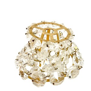 May include: A small, vintage chandelier lampshade with a gold-colored metal frame. The shade is adorned with numerous clear, faceted crystal beads, creating a sparkling, elegant appearance. The design is reminiscent of antique lighting fixtures.