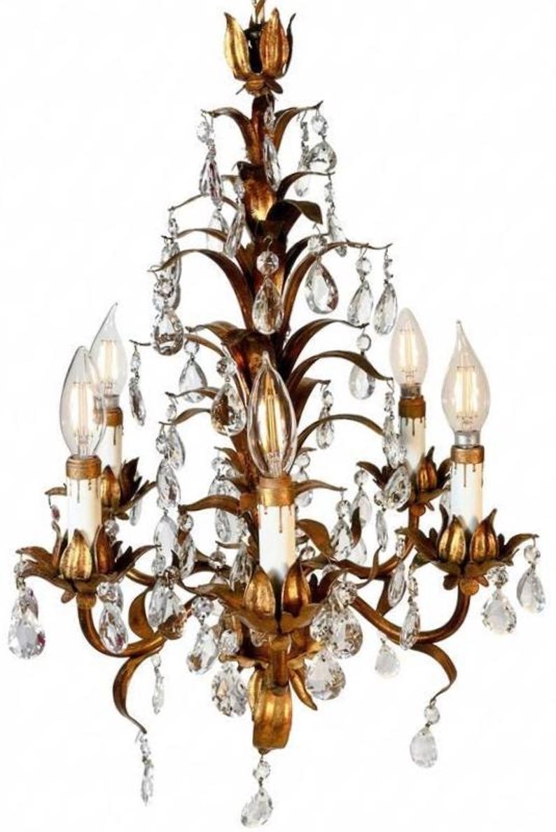 May include: Ornate gold chandelier with crystal accents. The fixture features multiple arms with candle-style light bulbs and dangling crystal droplets. The design has a vintage, elegant aesthetic, suitable for interior lighting.
