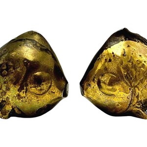 May include: Two metallic gold-toned fish figurines with textured scales and fins. Each fish is depicted in a swimming position with a rounded body, prominent eyes, and detailed tail fins. The surface of the metal shows a weathered, aged patina.