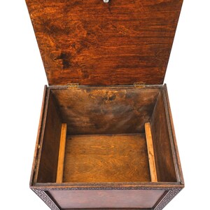 May include: An open, antique wooden chest with a hinged lid. The chest is stained a rich, dark brown color, with visible wood grain. The lid is slightly ajar, revealing the empty interior. The chest has decorative carvings around the top edge and sits on small feet.