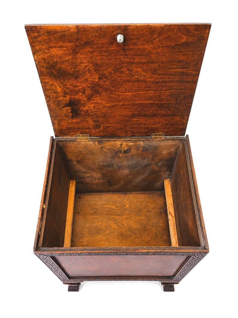 May include: An open, antique wooden chest with a hinged lid. The chest is stained a rich, dark brown color, with visible wood grain. The lid is slightly ajar, revealing the empty interior. The chest has decorative carvings around the top edge and sits on small feet.