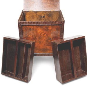 May include: A wooden chest with an open lid and two removable trays. The chest and trays are a rich, dark brown color, with visible wood grain. The chest has a decorative border around the top.