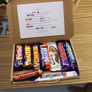 May include: A gift box containing a selection of chocolate bars such as Picnic, Lion, Yorkie, Double Decker, Galaxy, Wispa, Boost, and Rolo. The box also includes a handwritten note with a supportive message.