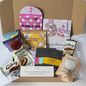 May include: A gift box containing a pink Bubble T sheet mask, gold eye masks, two duck-themed magnetic bookmarks, Border chocolate cookies, Galaxy instant chocolate, Taylors organic chamomile tea, a box of three soy tealights, and bath salts.