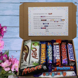 May include: A brown cardboard box filled with a variety of chocolate bars. The box is open and the chocolate bars are visible. The chocolate bars include Galaxy, Aero, Yorkie, Boost, Cadbury Double Decker, Wispa, Snickers, Mars, Curly Wurly, and Fudge.
