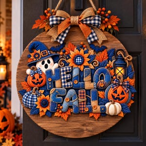 May include: A round wooden door sign featuring the text HELLO FALL in blue and tan fabric letters. The sign is decorated with a ghost in a blue hat, orange jack-o'-lanterns, sunflowers, blue leaves, a lantern, and a blue and tan plaid bow.
