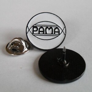 May include: A circular enamel pin featuring a white background with a black border and the text PAMA centered inside a black oval frame. The pin includes a separate silver-toned metal clutch backing and a black back side with a sharp metal pin post.