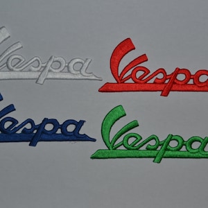 Op de afbeelding: Vier geborduurde strijklabels met het woord "Vespa" in wit, rood, blauw en groen.