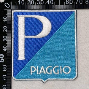 May include: A square embroidered patch featuring a diagonal split design with a dark blue upper section and a light blue lower section. A large white letter P is centered on the left, and the word PIAGGIO is stitched in white at the bottom.