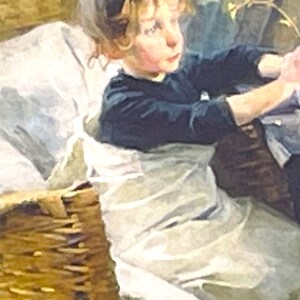 以下が含まれることがあります： 金髪の若い女の子が、籐のバスケットに座っています。白いドレスと濃い青色のセーターを着ています。彼女は右を見て、考え込んでいる表情をしています。