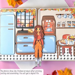 Pode incluir: Um conjunto de bonecas de papel imprim&iacute;veis com uma menina de cabelo castanho comprido vestindo uma roupa vermelha e laranja. A boneca est&aacute; em p&eacute; em frente a uma cena de cozinha com uma geladeira azul, uma pia e uma cafeteira. A cena da cozinha tamb&eacute;m inclui uma mesa com uma torta e um vaso de flores.