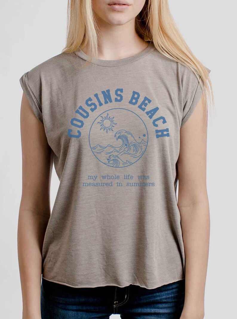 May include: A tan sleeveless t-shirt with the words "COUSINS BEACH" in blue, encircling a sun and wave graphic. Below, the text reads "my whole life was measured in summers."