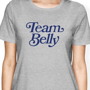 Op de afbeelding: Grijs T-shirt met de tekst "Team Belly" in een blauw retro-lettertype.