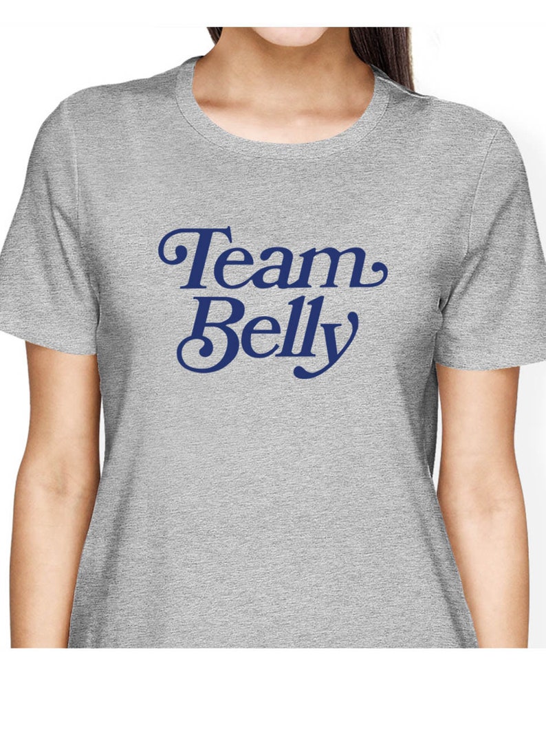 Op de afbeelding: Grijs T-shirt met de tekst "Team Belly" in een blauw retro-lettertype.