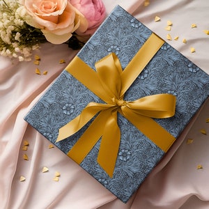 Gift wrapped in blue Marigold wrapping paper with wide gold ribbon bow on soft fabric background.