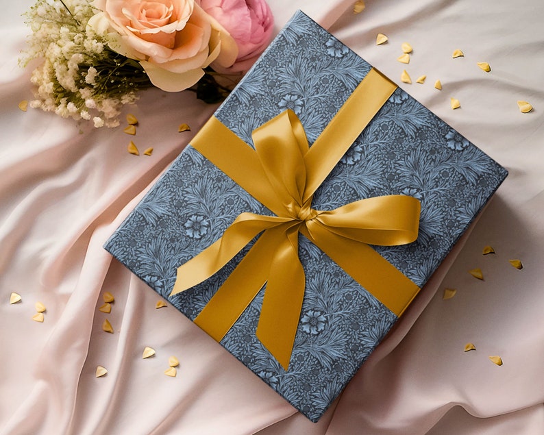 Gift wrapped in blue Marigold wrapping paper with wide gold ribbon bow on soft fabric background.