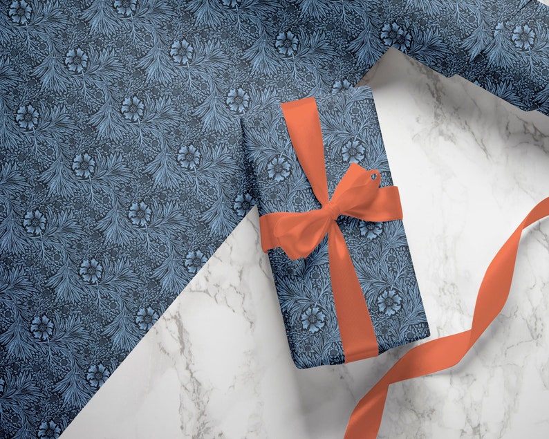 Blue Marigold floral wrapping paper sheet with wrapped gift tied in coral ribbon on marble surface.