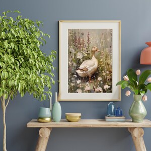 May include: A framed painting of a white duck standing in a field of wildflowers. The duck is facing to the right and has a brown beak. The flowers are in shades of pink, purple, and white.