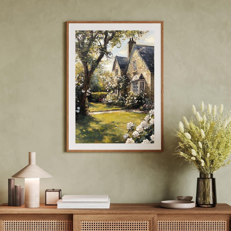 Puede incluir: Una pintura de una casa de campo de piedra con un c&eacute;sped verde y flores blancas en frente. La casa tiene un techo marr&oacute;n y una ventana con moldura blanca. La pintura est&aacute; enmarcada en un marco de madera marr&oacute;n.