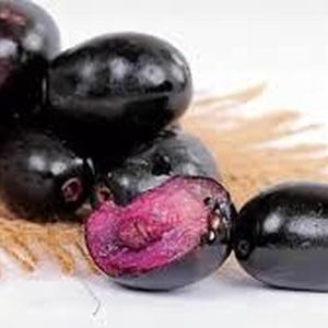 May include: A cluster of dark purple java plums, some whole and some cut open to reveal a vibrant magenta interior. The plums rest on a textured, tan surface, with a white background.