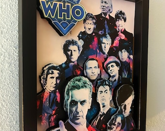 May include: Framed artwork featuring multiple portraits of the Doctor Who characters. The Doctor Who logo is at the top left. The artwork is in a black frame and is mounted on a white wall.