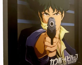 May include: A framed 3D shadow box art piece featuring an anime character with dark hair pointing a handgun directly forward. The character wears a dark blue jacket and yellow shirt. The text Cowboy Bebop is printed in Japanese and English.