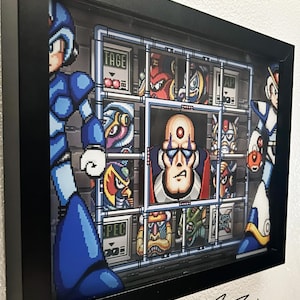 May include: A framed 3D pixel art piece featuring characters from the Mega Man X video game series. The artwork is encased in a black frame and includes the artist's signature and the text "FANBIT CREATIONS". The characters are in a grid-like layout.